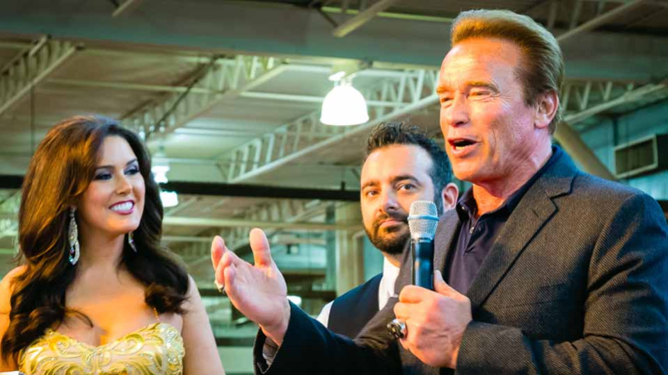 Arnold talking to a crowd of people with a microphone.