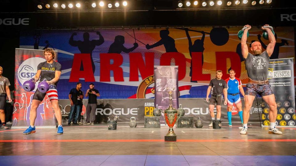 Kettlebell competition on stage with a trophy.
